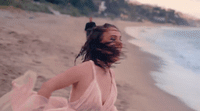 a woman in a pink dress on a beach