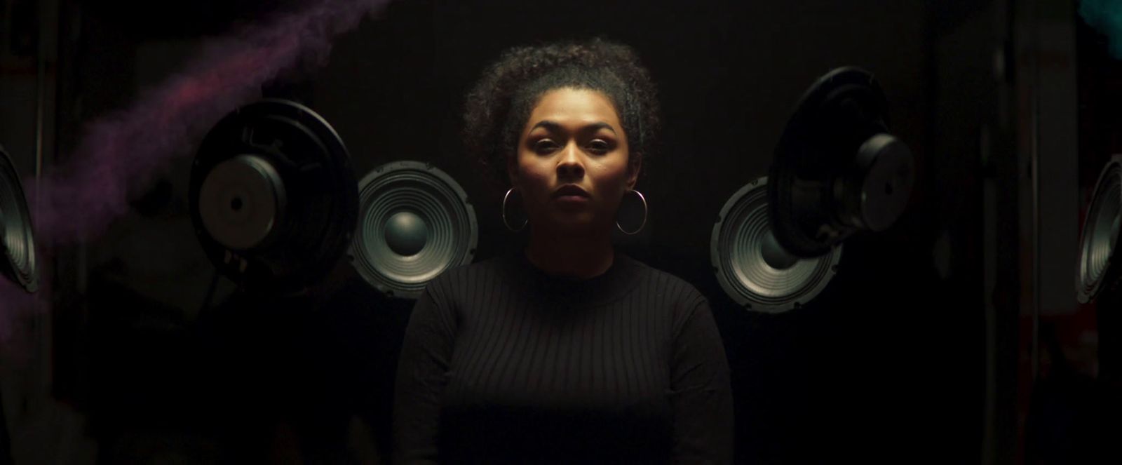 a woman standing in front of speakers in a dark room