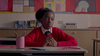 a young girl sitting at a desk in a classroom