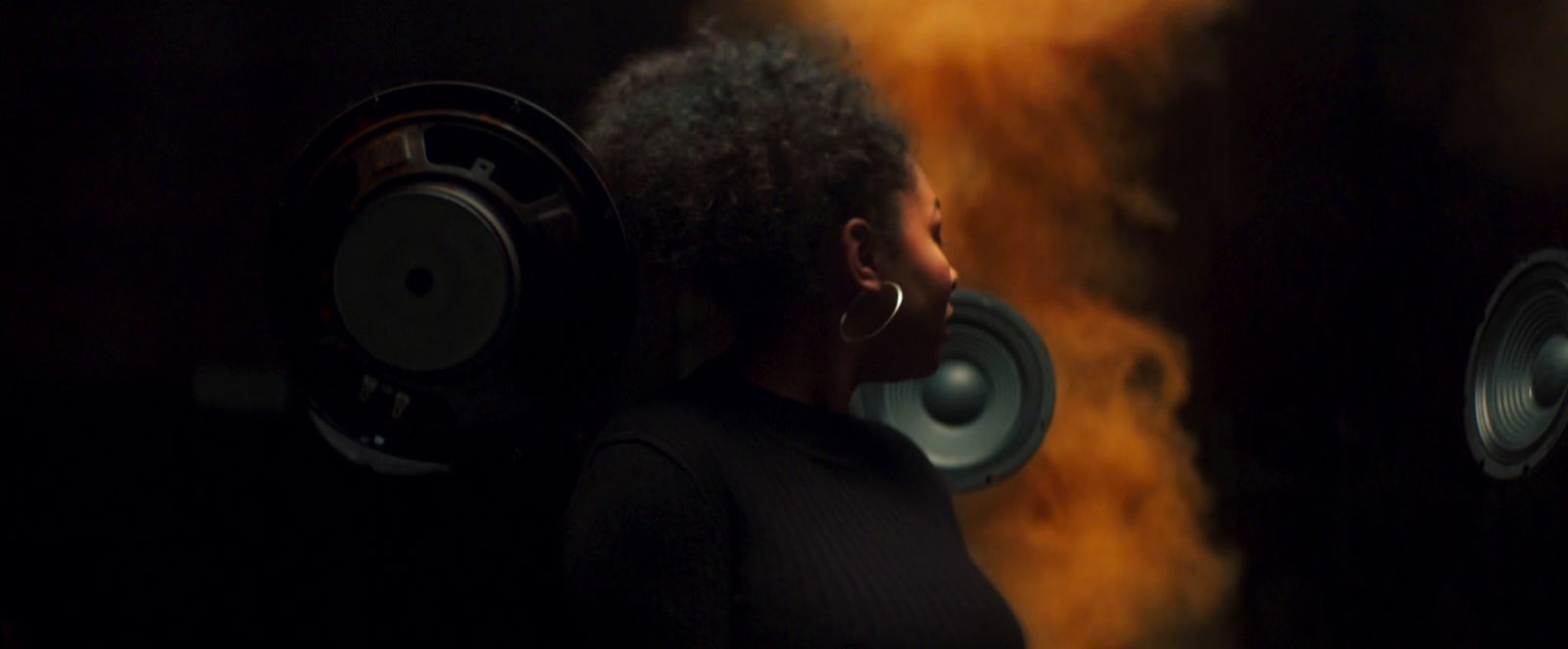 a woman with headphones standing in front of speakers