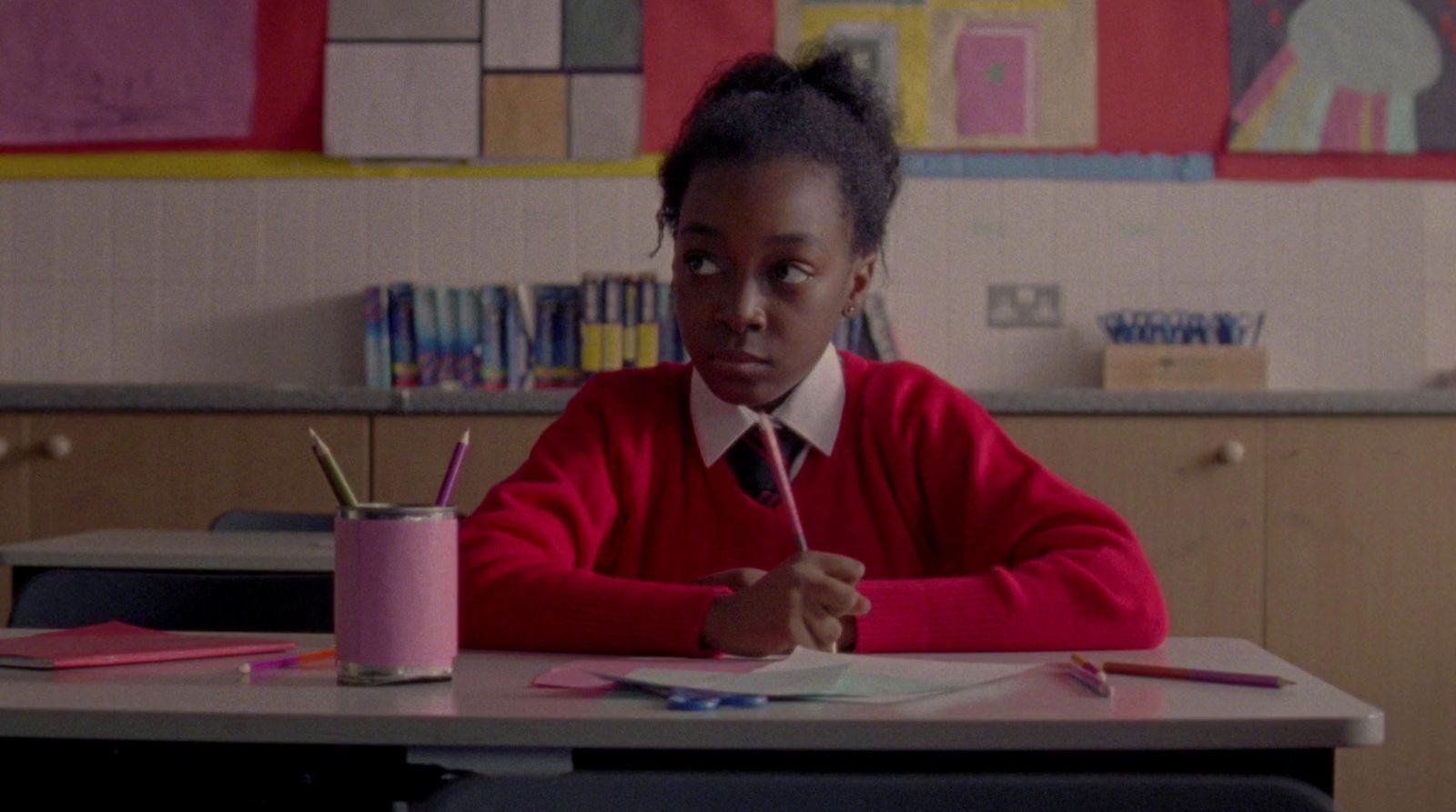 a young girl sitting at a desk in a classroom