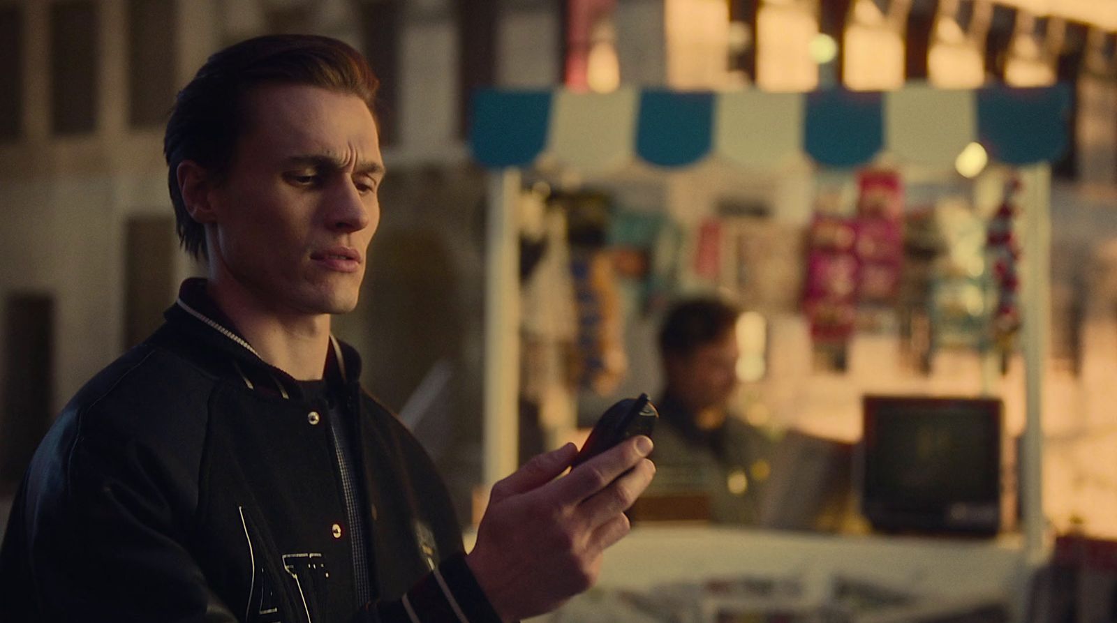 a man standing in front of a store looking at his cell phone