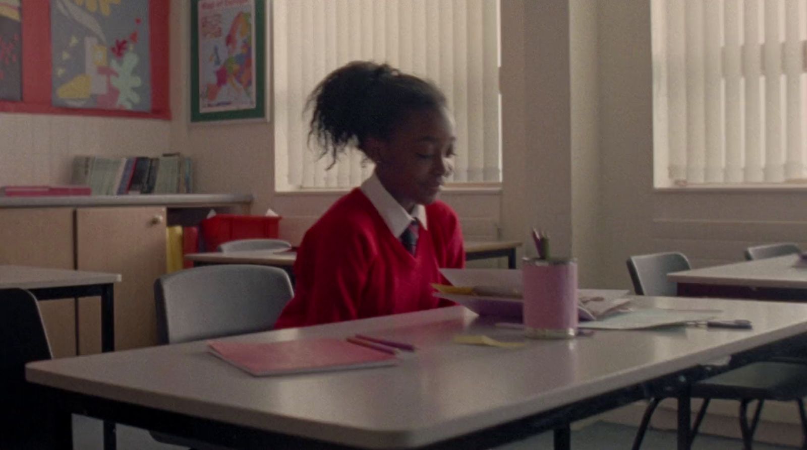 a young girl sitting at a table in a classroom