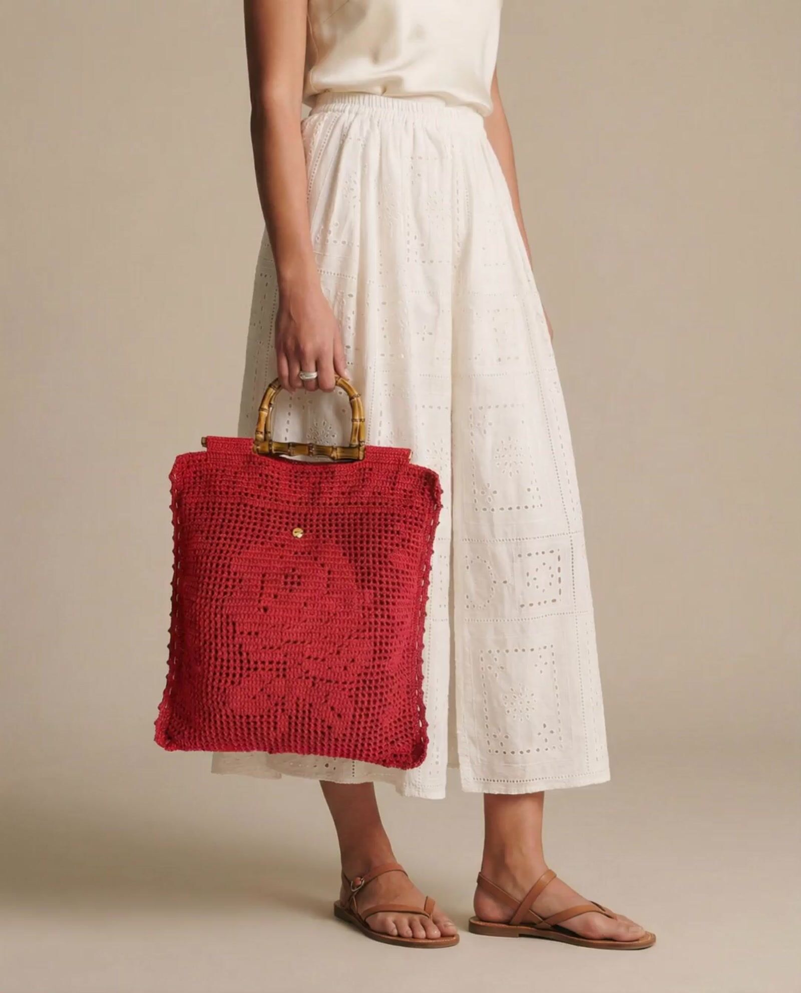a woman in a white dress holding a red purse