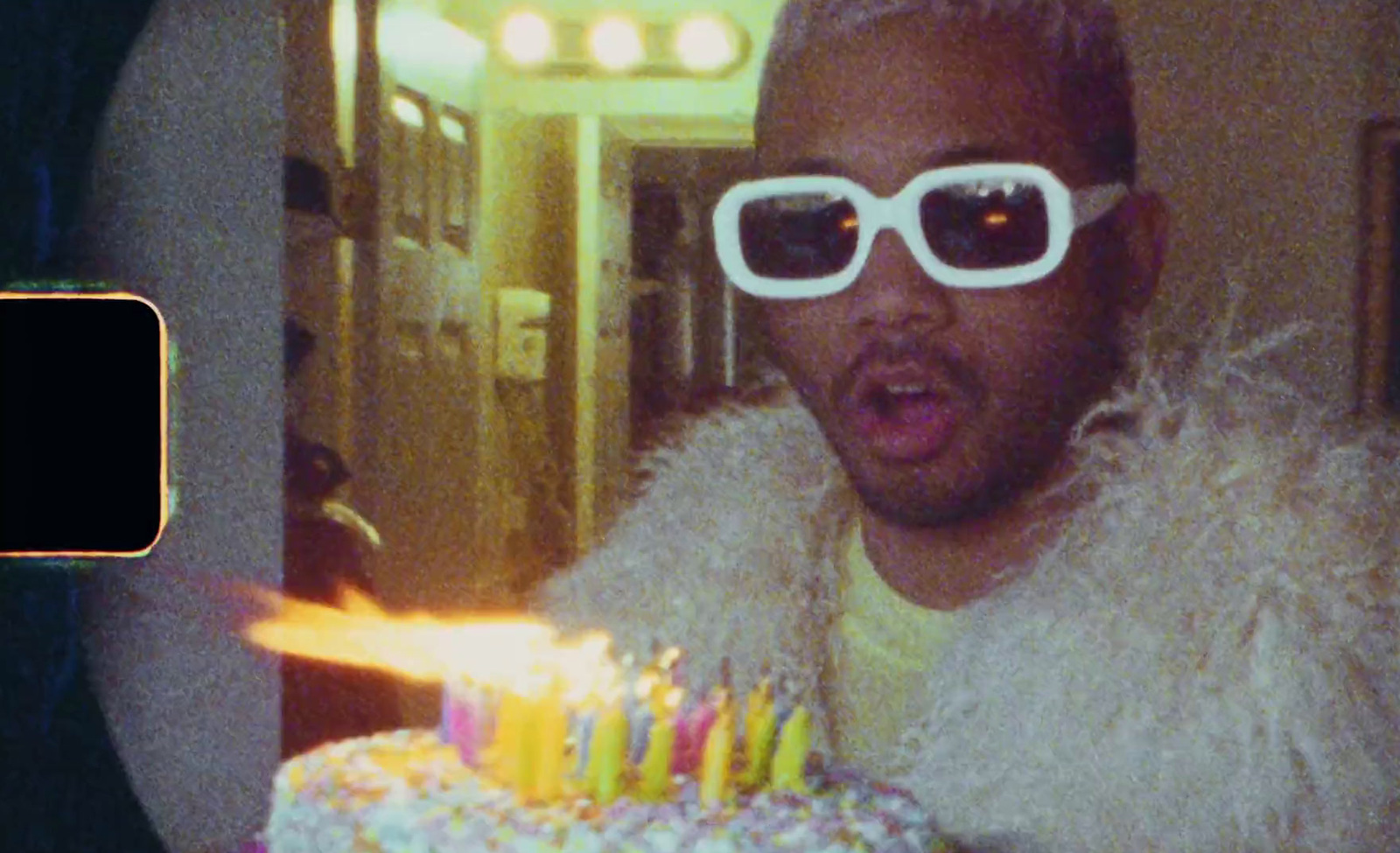 a man wearing sunglasses blowing out candles on a cake