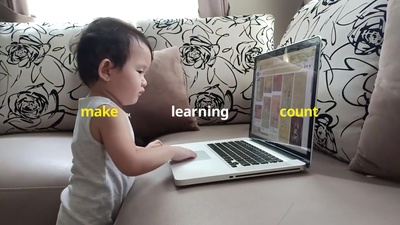 a little boy sitting on a couch using a laptop