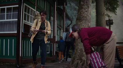 a woman looking at her cell phone while standing next to a tree