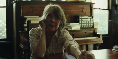 a woman sitting at a table in front of a piano