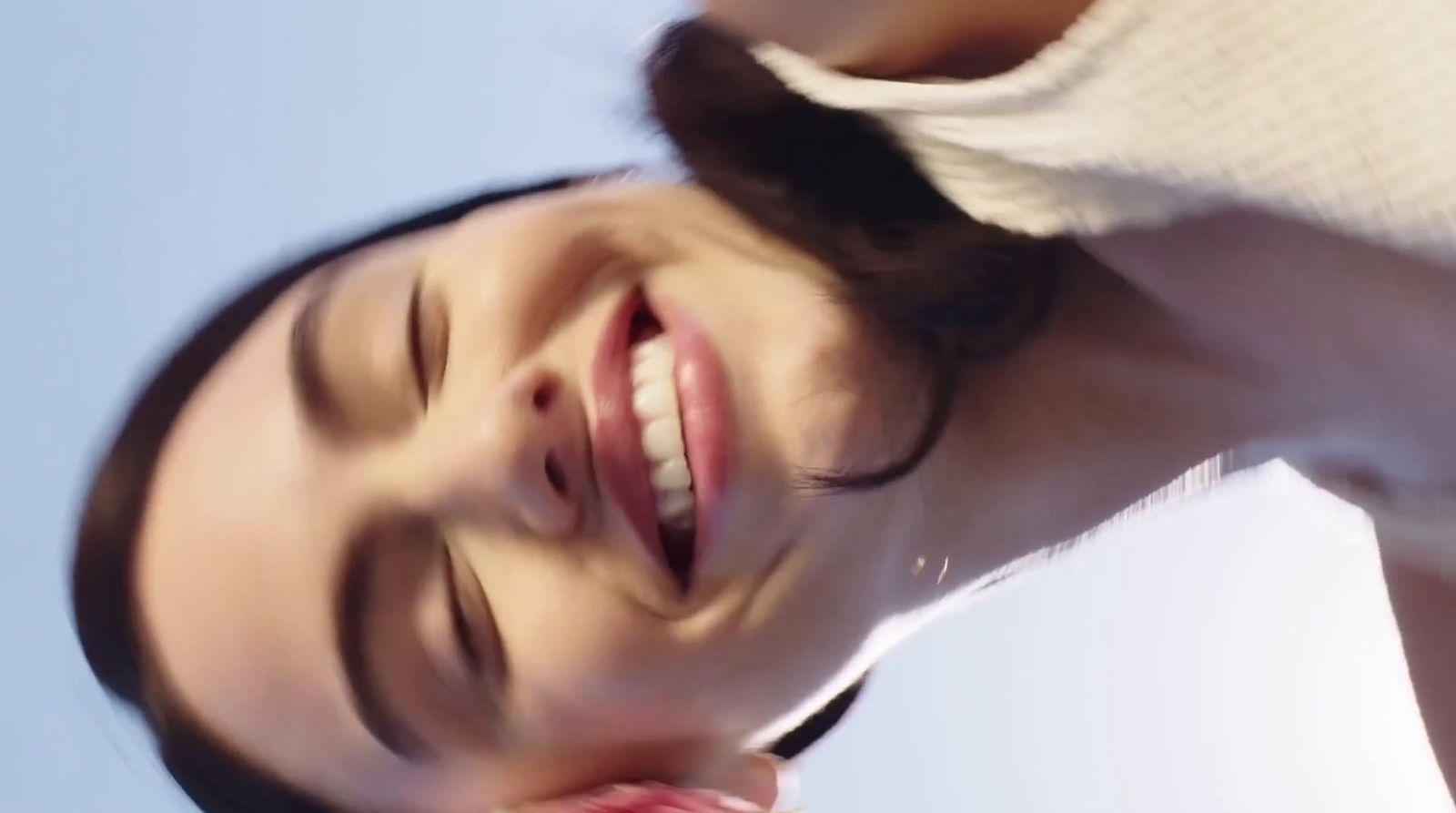 a woman smiling and holding a cell phone to her ear