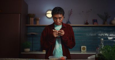 a woman standing in a kitchen looking at her cell phone