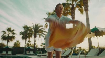 a man standing next to a swimming pool holding a frisbee