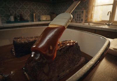 a person dipping sauce on a piece of chocolate cake