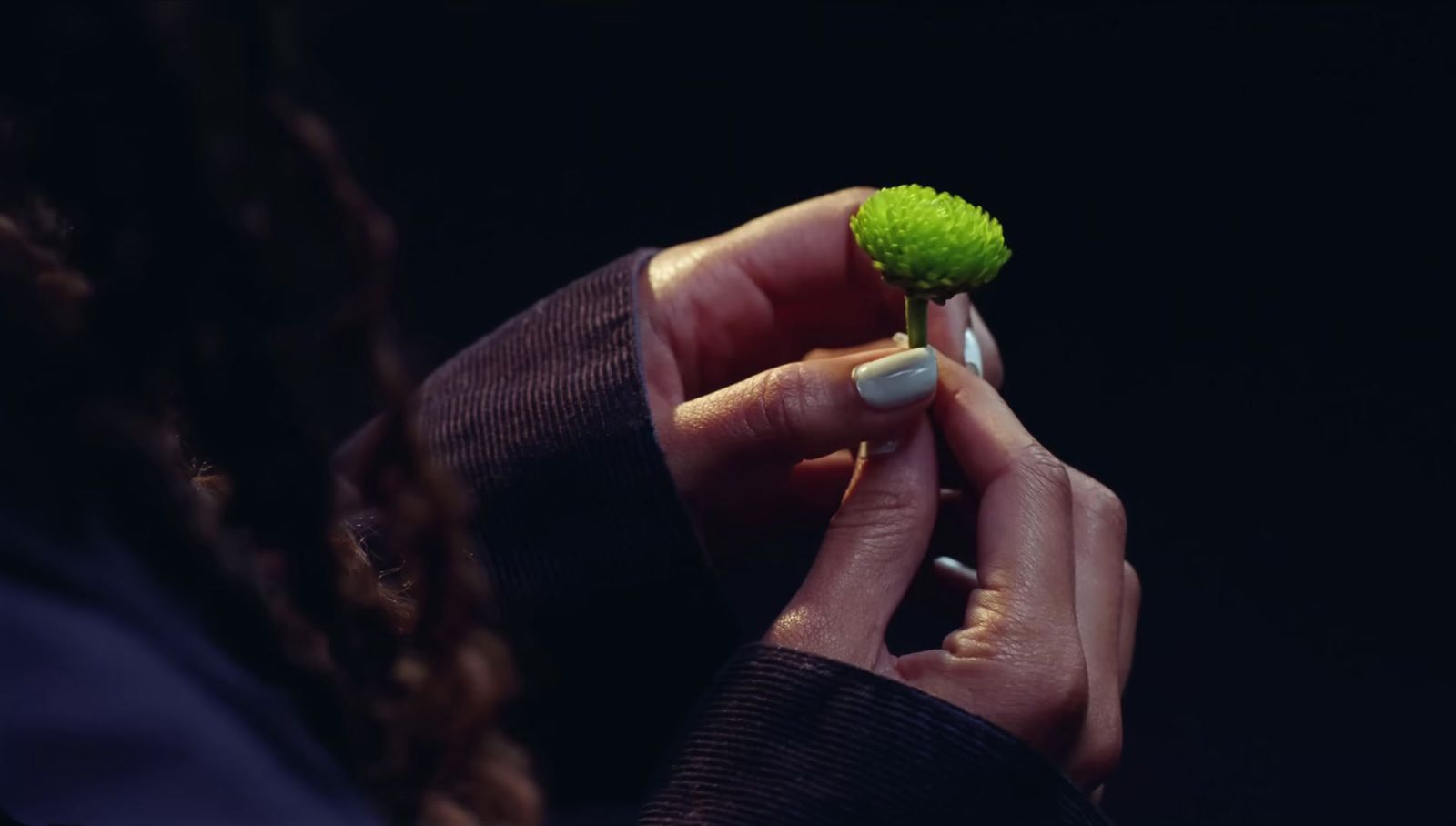 a woman holding a green flower in her hand