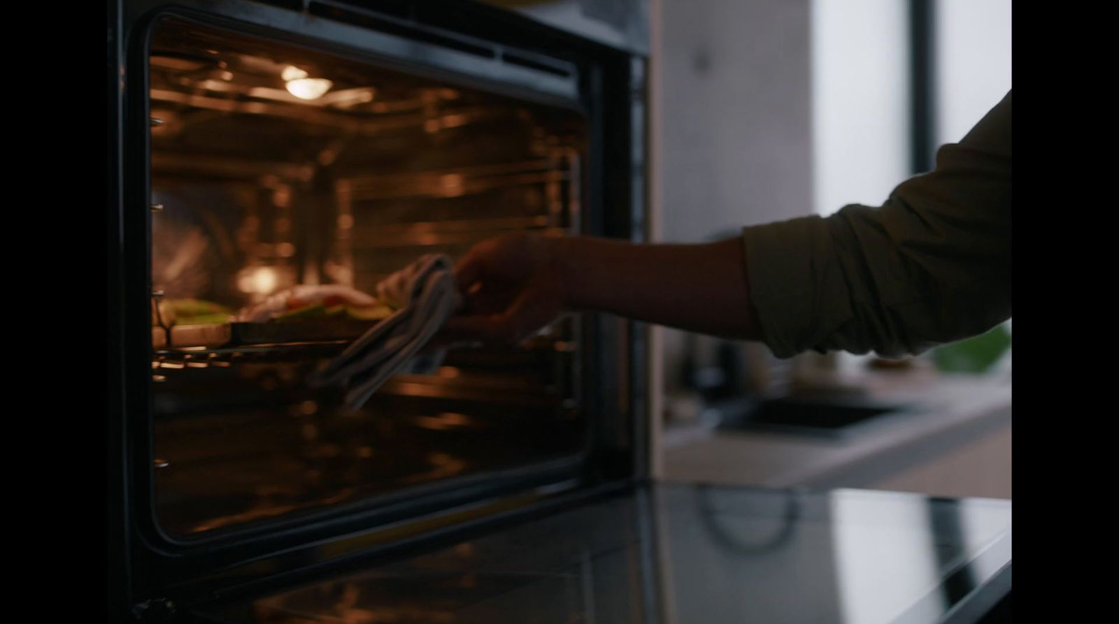 a person taking a piece of food out of an oven