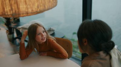 two girls sitting at a table talking to each other