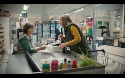 a woman paying a customer in a grocery store