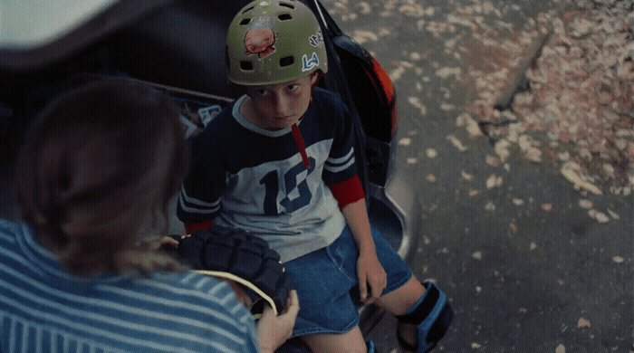 a young boy sitting on a scooter with a helmet on