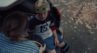 a young boy sitting on a scooter with a helmet on