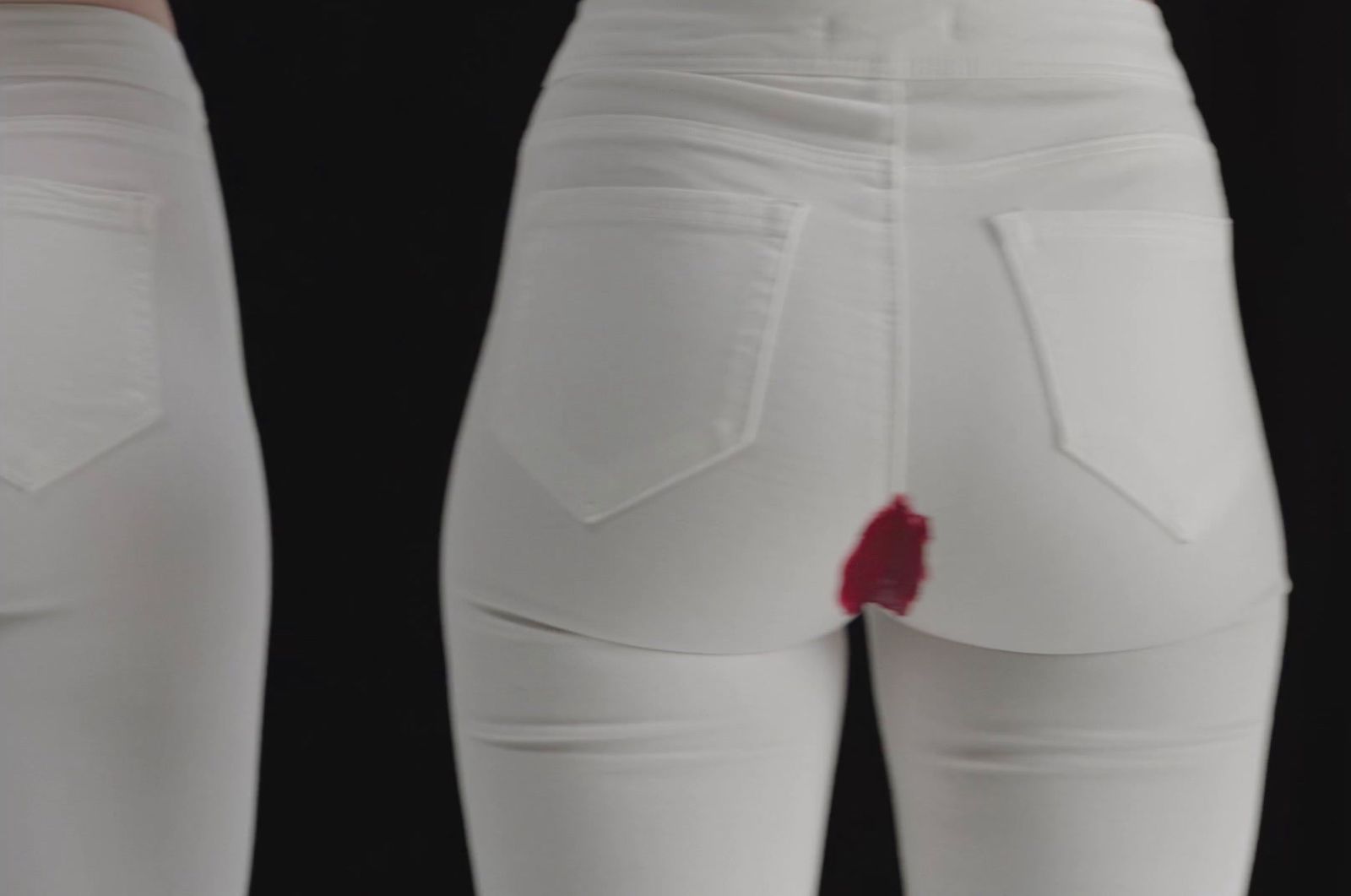 a pair of white jeans with a red patch on the side