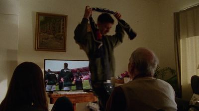 a man holding a tie in front of a tv