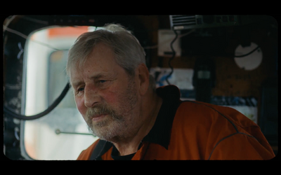 a man in an orange shirt looking out a window