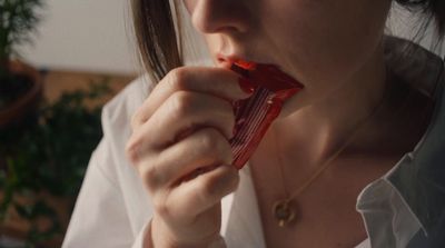 a woman holding a candy bar in her mouth