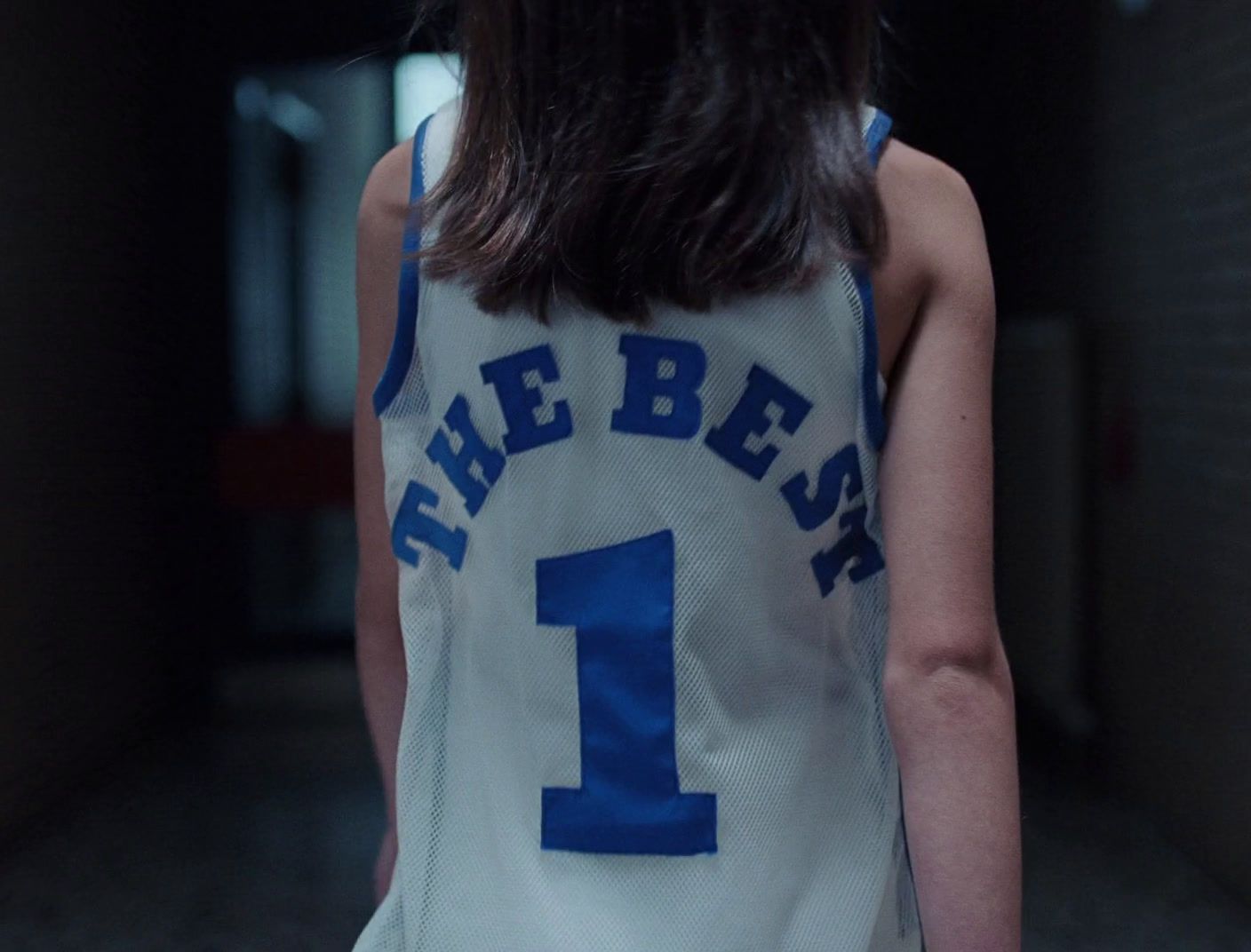 a girl in a basketball jersey is standing in a hallway