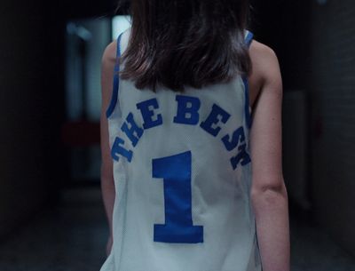 a girl in a basketball jersey is standing in a hallway