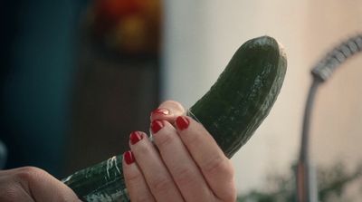 a woman holding a cucumber in her hand