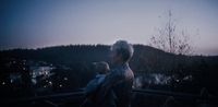 a man holding a baby on a balcony at night
