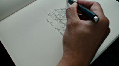 a person writing on a piece of paper with a pen