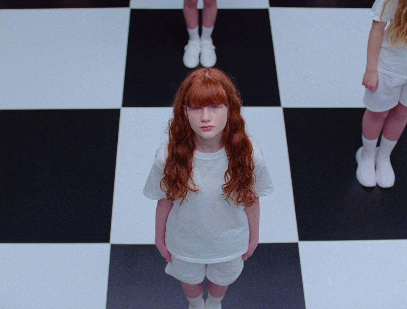 a girl with red hair standing on a black and white checkered floor