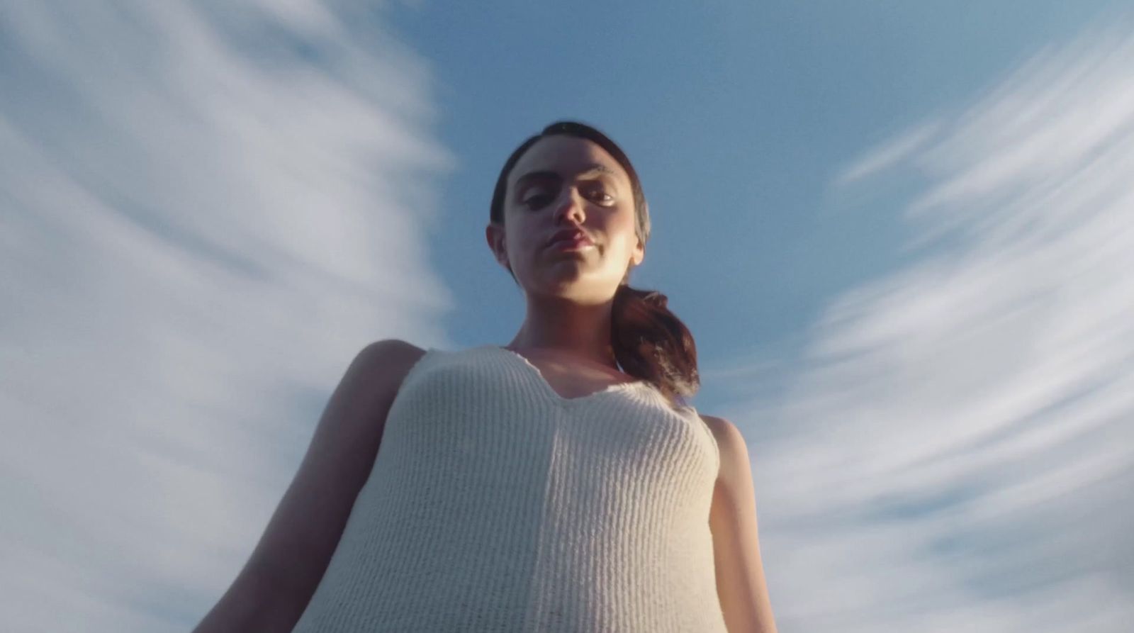 a woman standing in front of a cloud filled sky