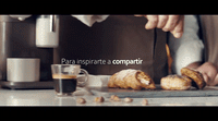 a person preparing pastries on a cutting board next to a cup of coffee