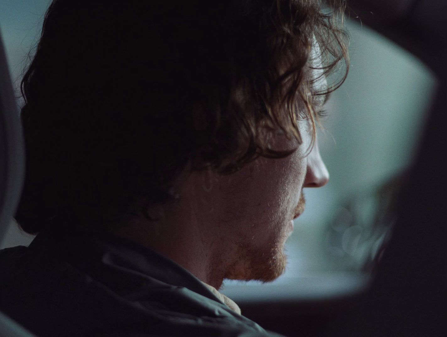 a man sitting in a car looking out the window