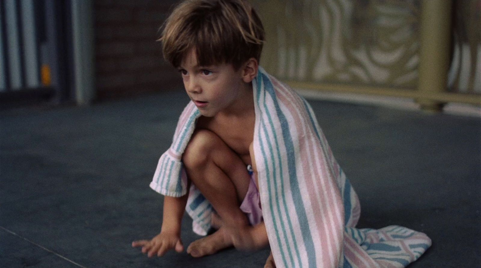 a young boy sitting on the floor wrapped in a towel