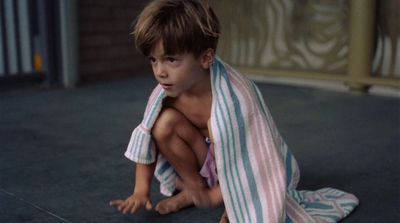 a young boy sitting on the floor wrapped in a towel