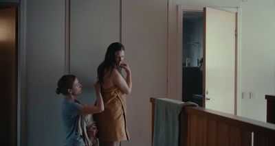 a woman standing next to a woman brushing her teeth