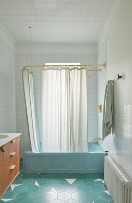 a bathroom with a blue bathtub and a white curtain