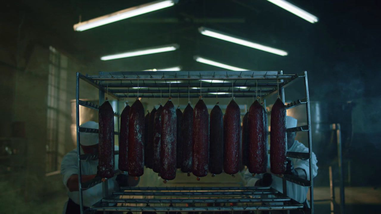 a man in a white shirt and some sausages on a rack