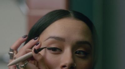 a woman is putting on makeup with a brush