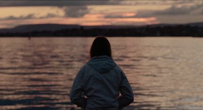 a woman standing on the shore of a body of water