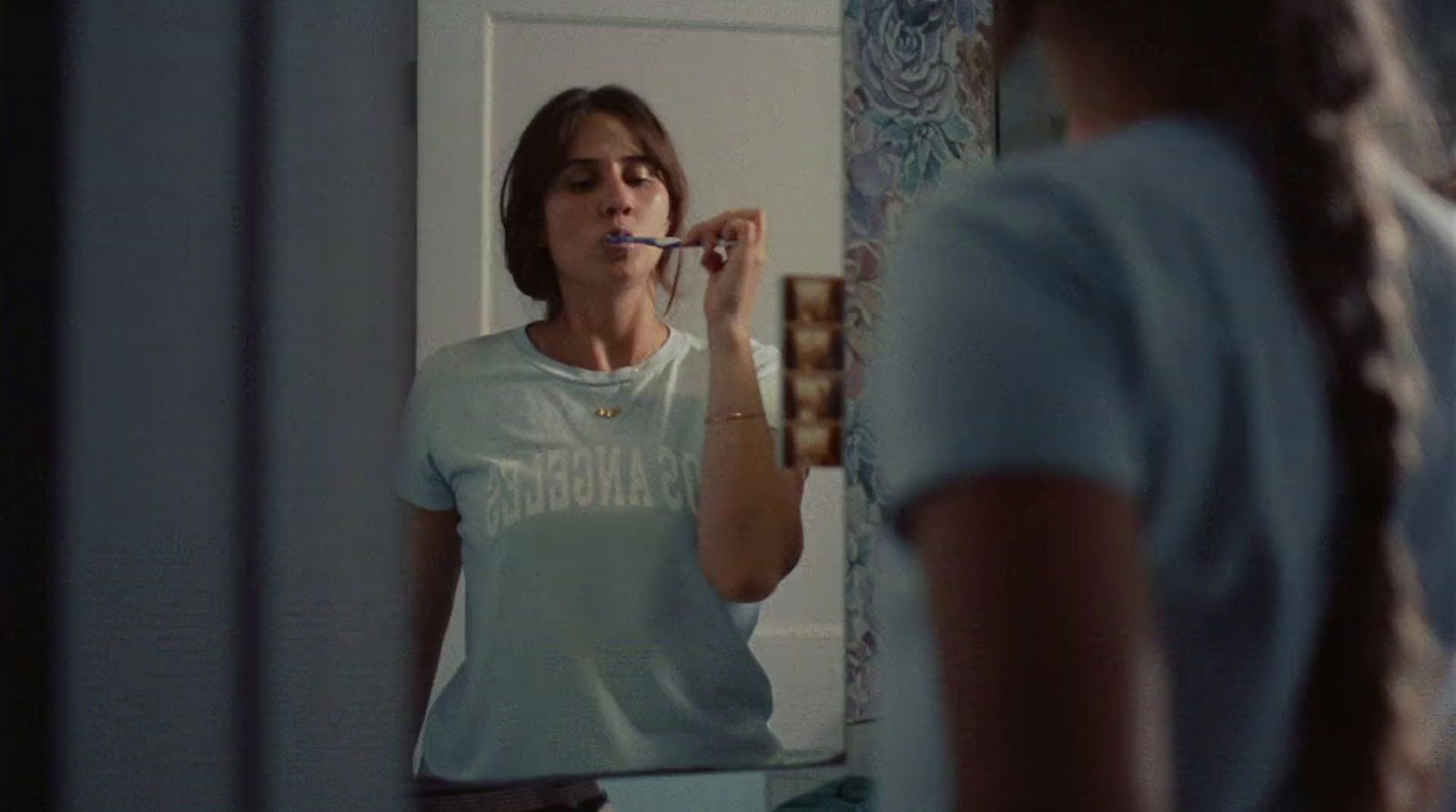 a woman brushing her teeth in front of a mirror