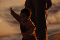 a little boy standing next to a man on a beach