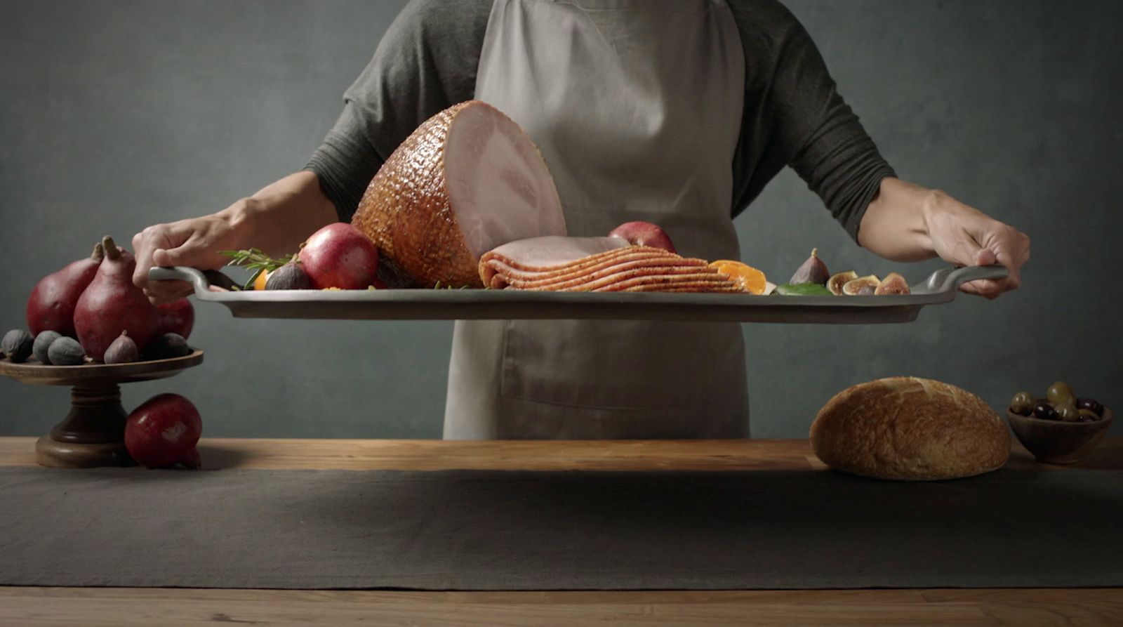 a woman in an apron holding a platter of food