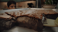 a person holding a fork in front of a chocolate cake