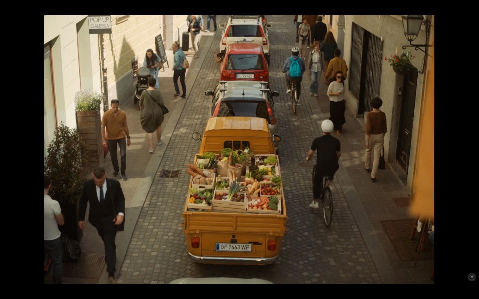 a group of people walking down a street next to parked cars