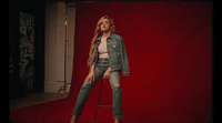 a woman standing on a stool in front of a red wall