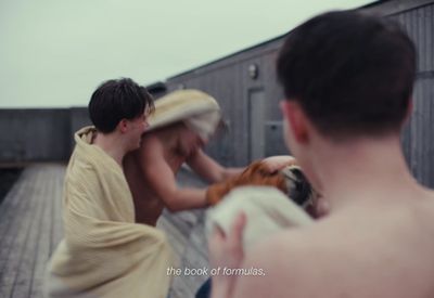 a man and a woman holding a dog on a dock