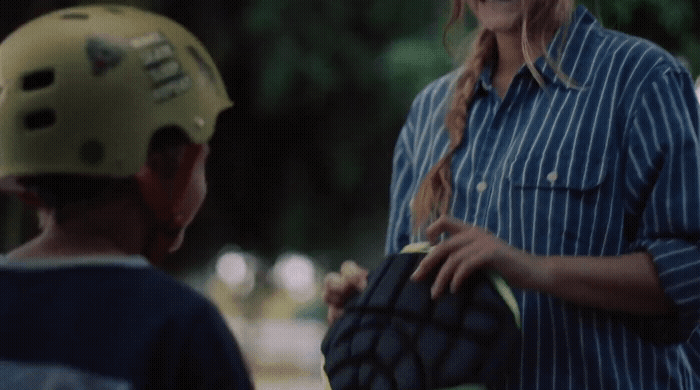 a woman holding a catchers mitt next to a young boy
